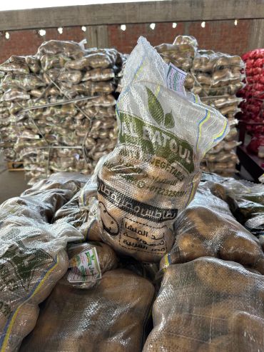 Bags of potatoes stacked in a warehouse setting.