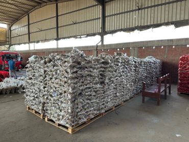 Large stacks of packaged goods on wooden pallets inside a warehouse.