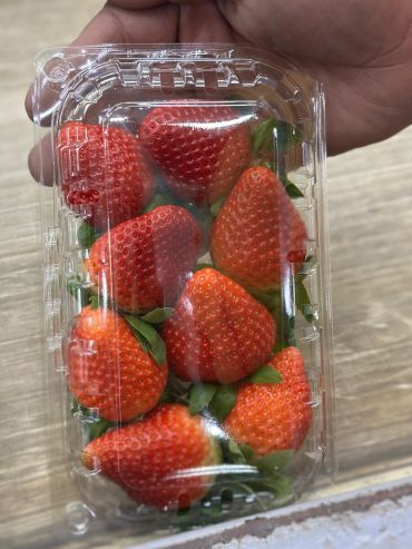 Fresh strawberries packed in a clear plastic container.