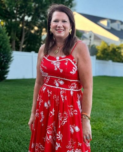 Woman smiling outdoors in a red dress.