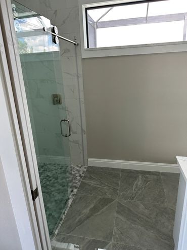Modern bathroom with glass shower enclosure and marble tiles.