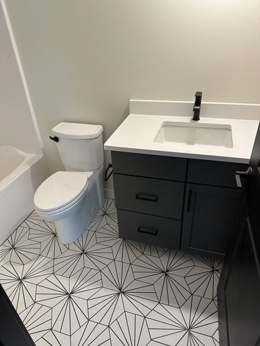 Modern bathroom with geometric floor tiles and sleek black fixtures.