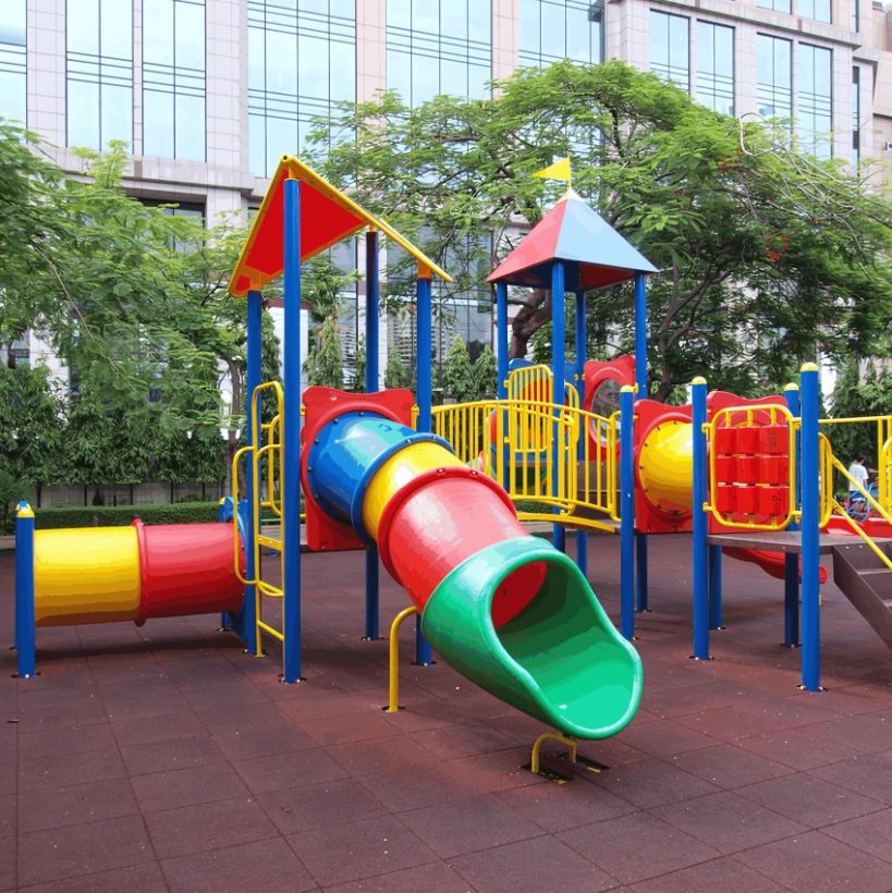 A colorful playground set with slides and tunnels in an urban park.