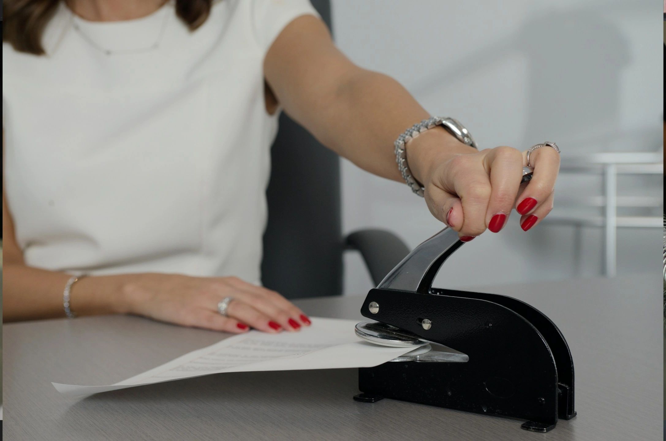 Woman using a hole puncher on paper.
