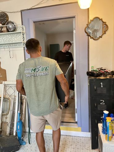 Two men carrying a large box into a room.