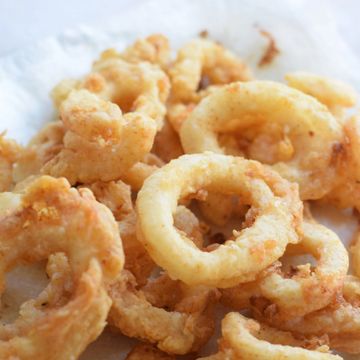 Close-up of crispy fried calamari rings on a white surface.