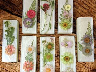 Handmade resin hair clips with embedded dried flowers on wooden surface.