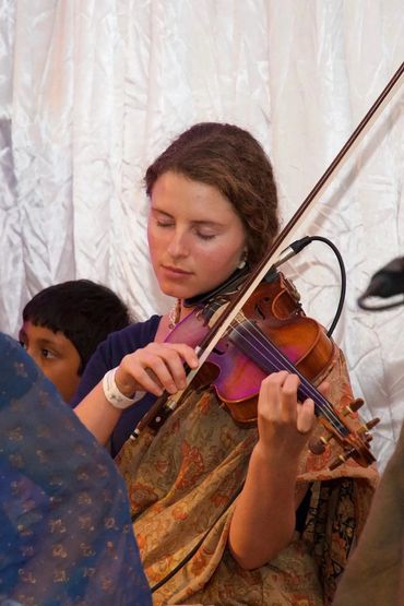 A woman playing the violin with eyes closed, immersed in music.