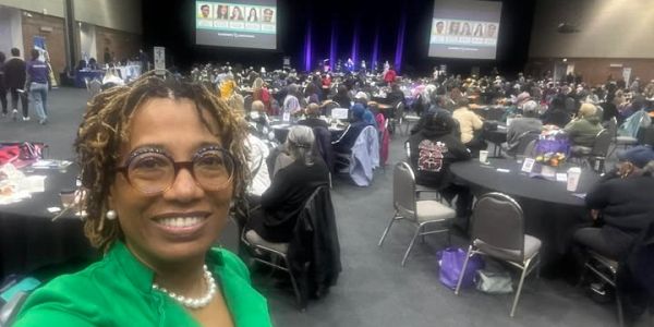 Woman in green taking selfie at conference.