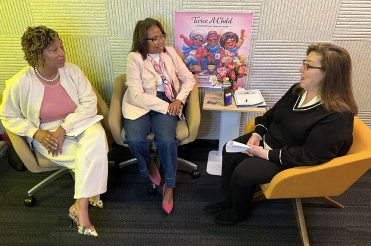 Three women engaged in a conversation while seated in an office setting.