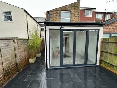 Modern conservatory extension with aluminium bifold doors and new patio area completed in Hanwell, W