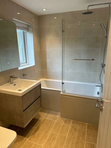 Modern family bathroom with bath, shower screen, wall-hung vanity unit and large tiles in Northwood