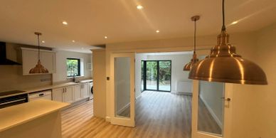 Open-plan kitchen and living room extension with kitchen island and glazed doors in Northwood HA6.