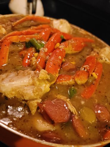 Close-up of a crab and sausage stew with vegetables.