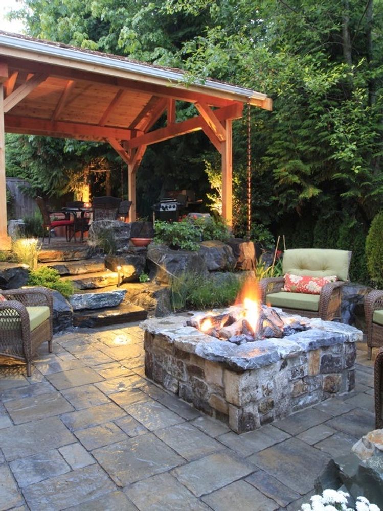 Cozy outdoor patio with stone fire pit and wooden pergola.