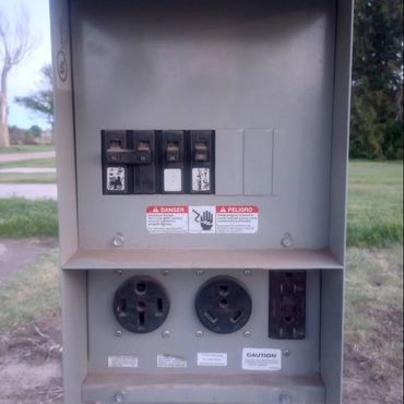 Electrical panel with switches and various power outlets outdoors.