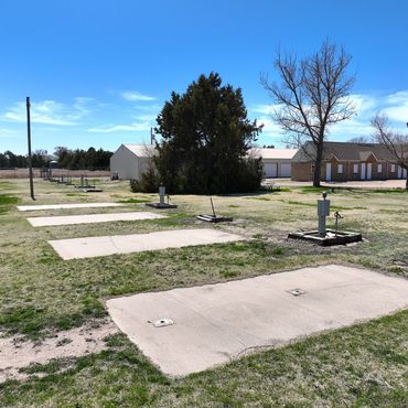 Empty RV hookups in a grassy campground under a clear blue sky.