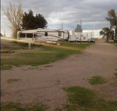 RVs parked on a gravel and grass lot under a cloudy sky.