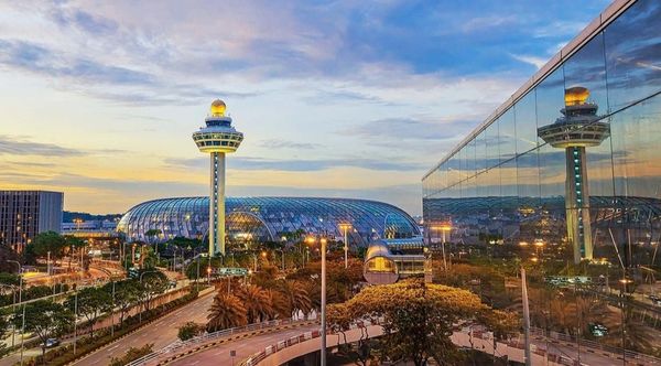 Modern airport with a glass dome and control tower at sunset.