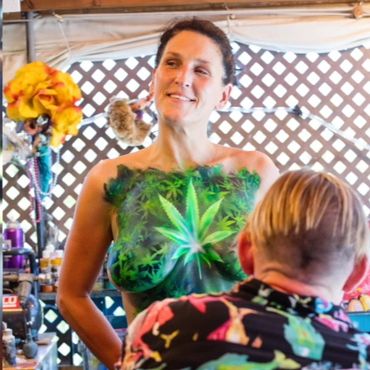 Woman with detailed marijuana leaf body paint on her chest.