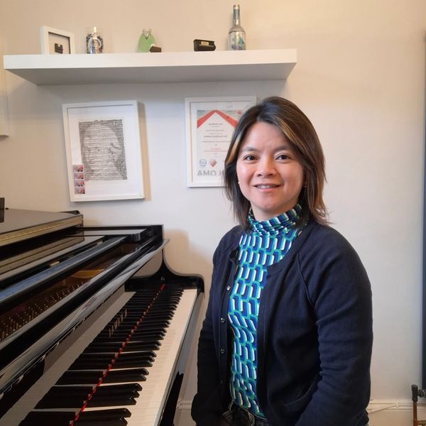 Woman sitting next to a piano, smiling.