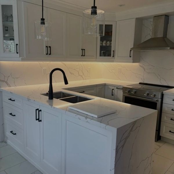 Modern kitchen with white marble countertops and black fixtures.