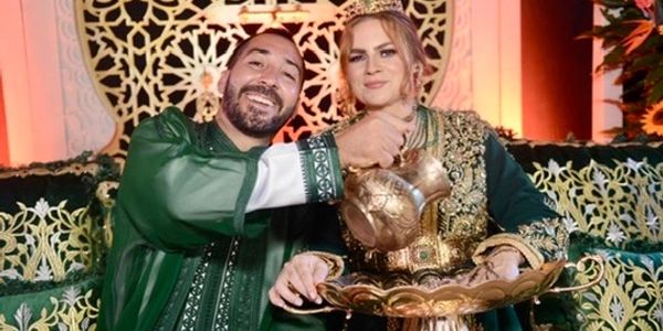 Berber groom and American bride participating in traditional Moroccan wedding ceremony with henna