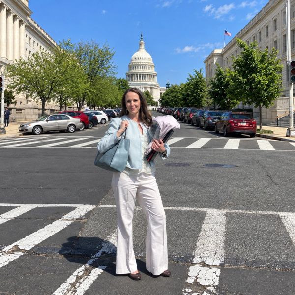 Woman standing on a street with the Capitol building behind her.