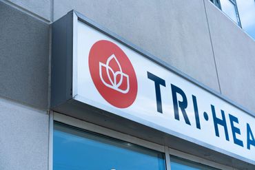 Close-up of a sign with a red circular logo and partial text on a building.