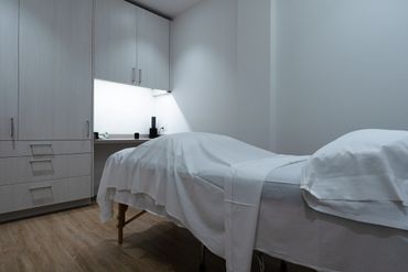 Minimalist treatment room with a massage table and storage cabinets.