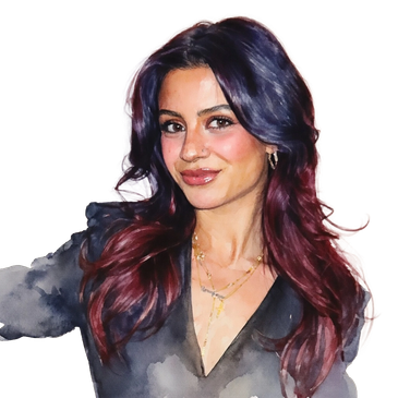 A confident woman with dark purple and red hair wearing gold jewelry and a dark blouse.