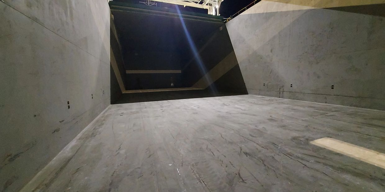 Empty large cargo container or ship hold with open hatch at night.