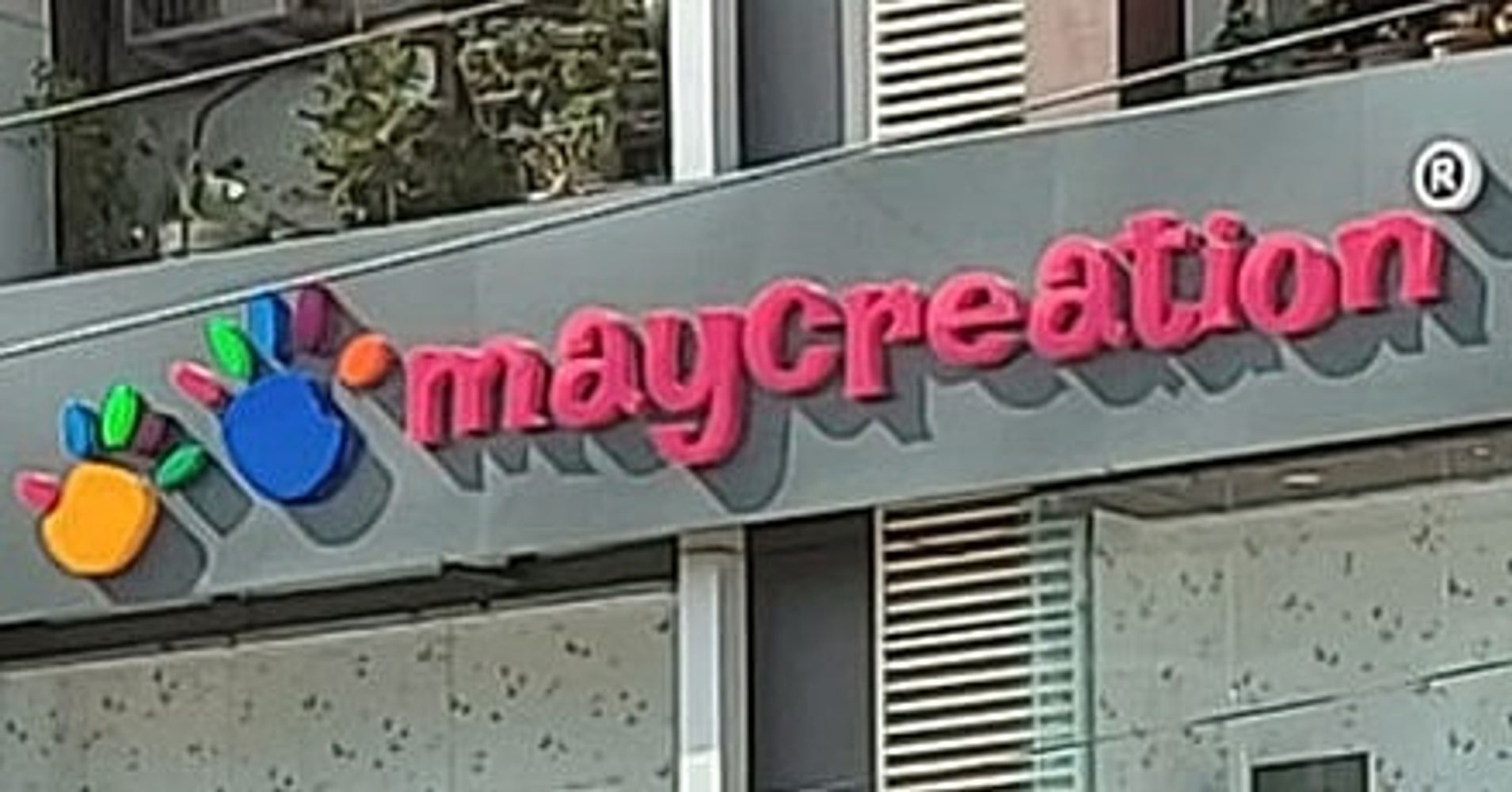 Colorful logo and red text reading 'maycreation' on a building sign.