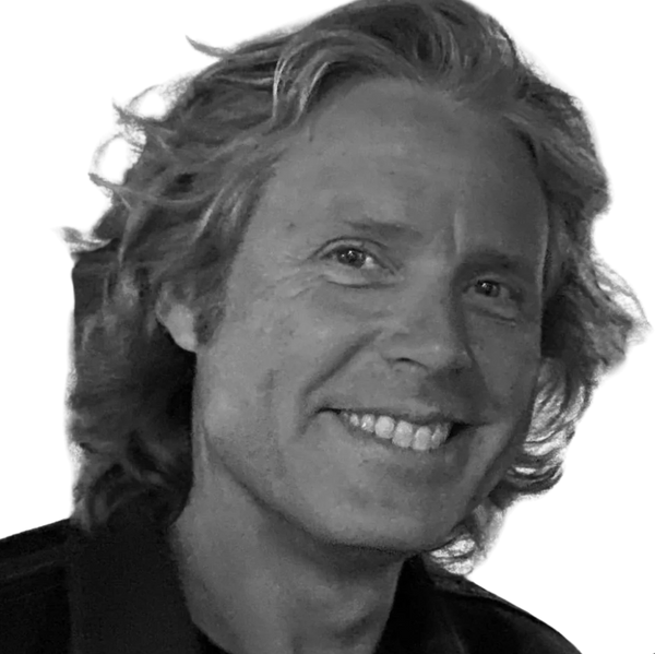 Black and white close-up of a smiling man with wavy hair.