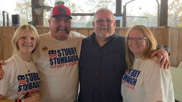 Four people posing together, three wearing 'Stubby Stumbaugh County Judge' shirts.