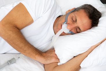 Man sleeping with CPAP mask for sleep apnea therapy.