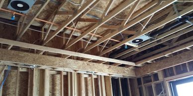 Exposed wooden framing and electrical wiring in a building under construction.