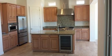 Modern kitchen with wooden cabinets and a central island with granite countertop.