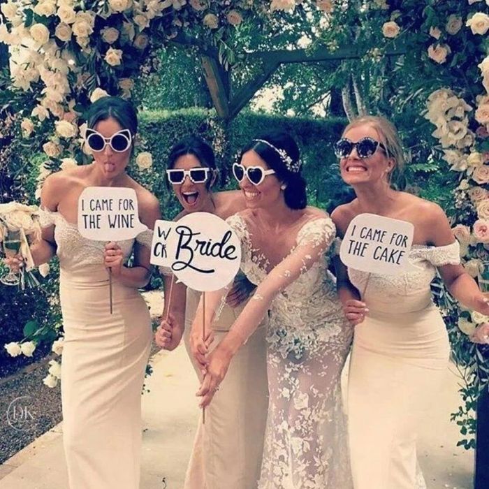Bride and bridesmaids posing with funny signs at wedding.