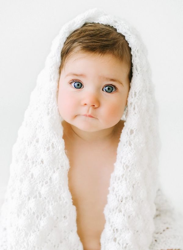 A baby wrapped in a white knitted blanket.