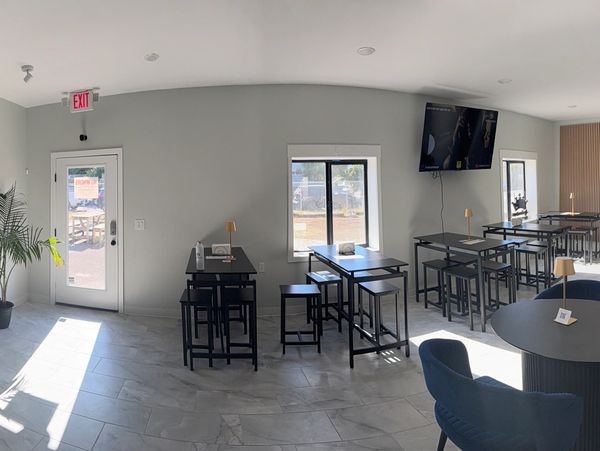 Modern social lounge with blue seating, black tables, and bright natural light.