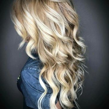 Photo of client facing away with long blonde hair, curled with highlights and lowlights.