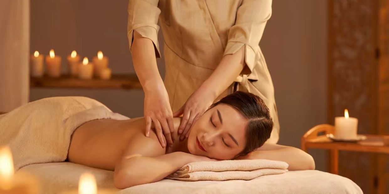 Woman getting a relaxing back massage in a candlelit spa.