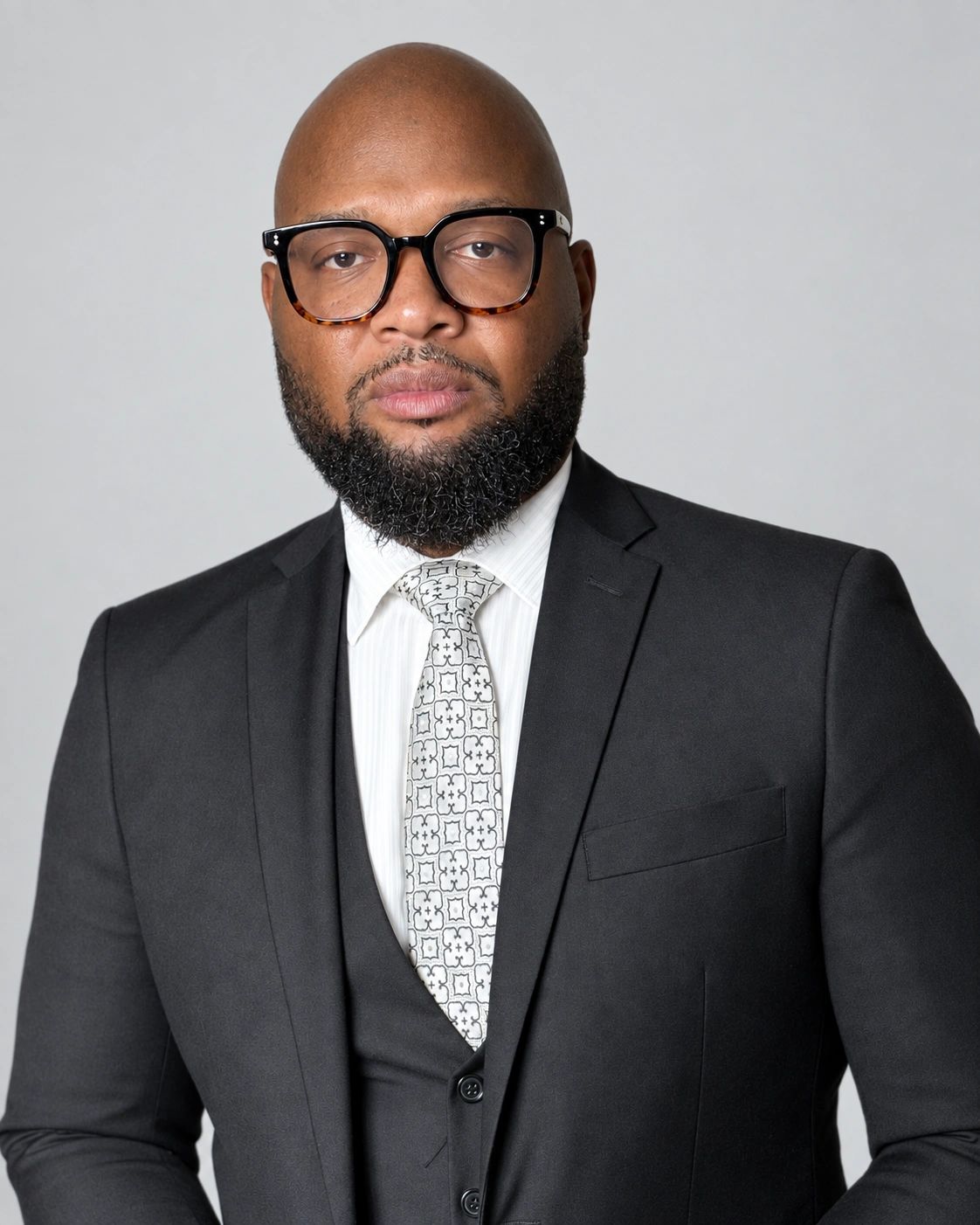 Confident man in black suit and patterned tie.