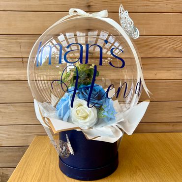 Navy blue hat box with clear balloon. Florals inside the balloon an silver butterfly decoration.