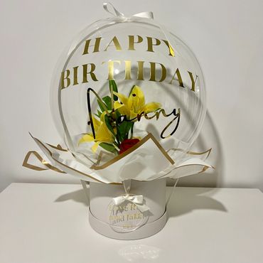 White hat box bubble balloon with red rose and lilys inside. Personalised with gold writing.