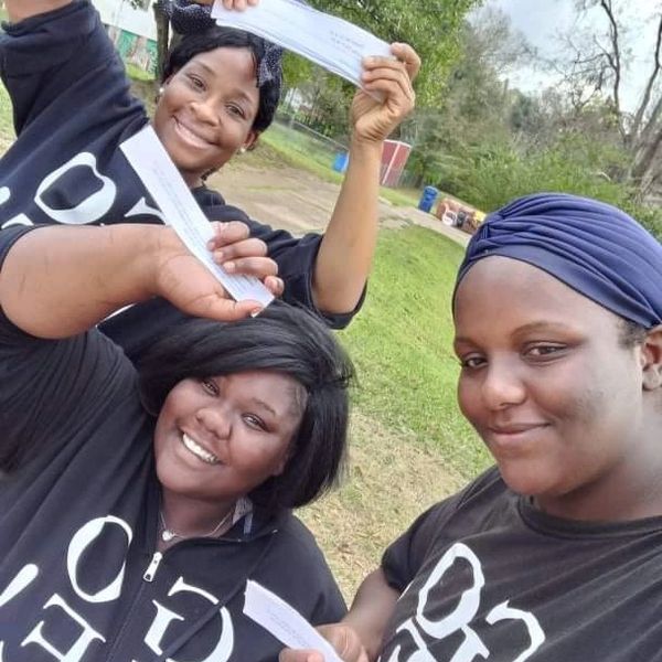 Three female residents showing the fruit of their labor, holding up paycheck.