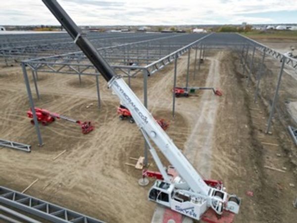 Construction site with cranes assembling metal framework for a large structure.