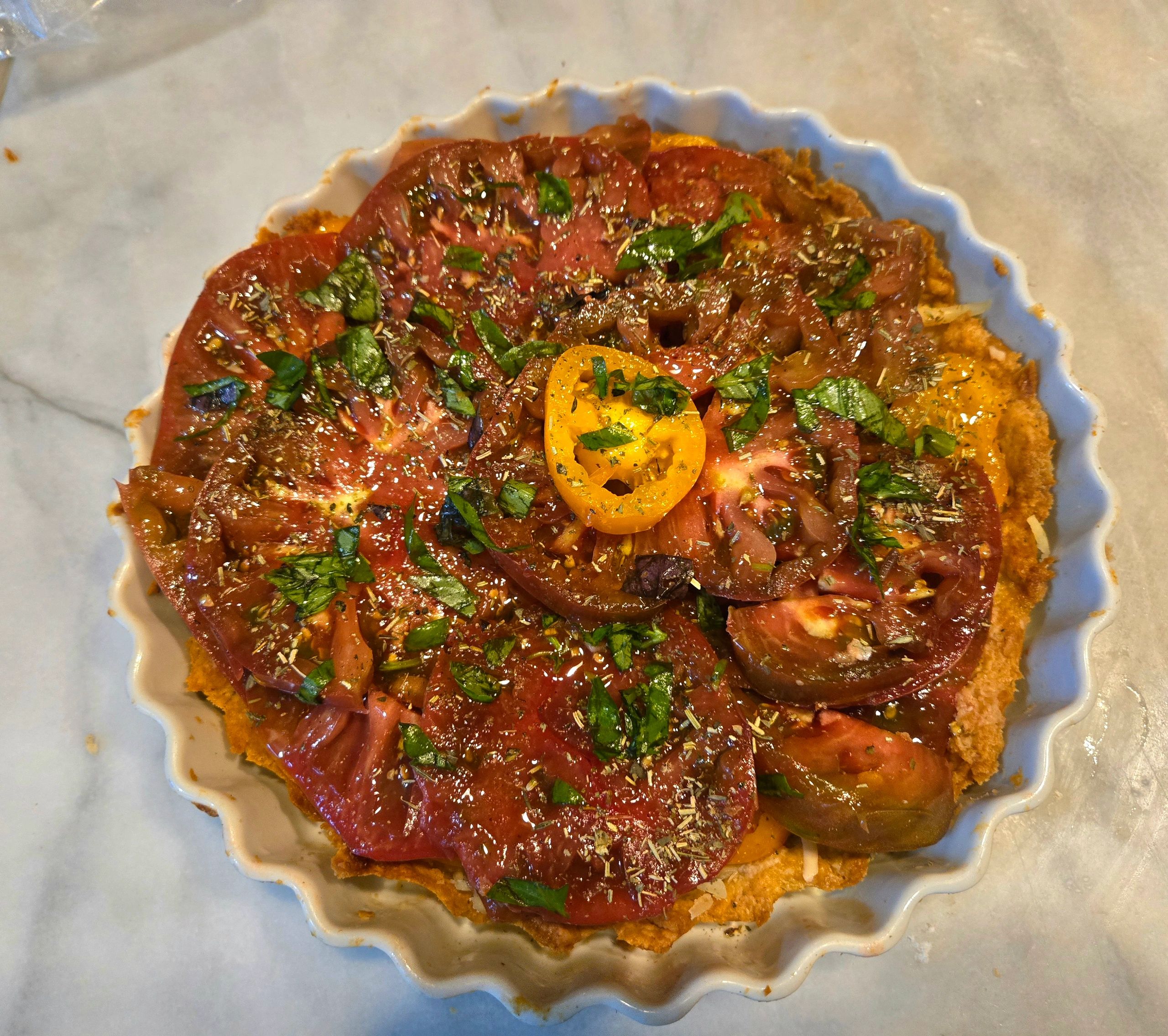 Tomato tart garnished with fresh herbs in a fluted dish.