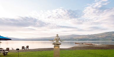 Namaste statue in front of a lake